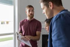 Un professionnel montre à un jeune couple des informations importantes mentionnées sur un document 