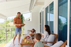 Un couple profite avec ses deux enfants de sa terrasse abritée par un store banne