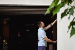 Un homme se tient à l'entrée de son garage, avec la porte ouverte sur l'intérieur