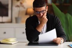 Un homme assis à un bureau découvre le contenu d'un courrier