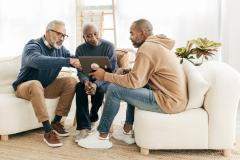 Un couple de personnes âgées échange avec un homme plus jeune et commente les informations fournies sur une tablette