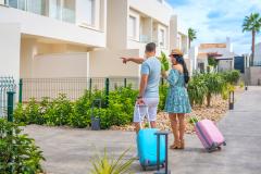 Un homme et une femme avec leurs valises colorées montrent leur lieu de vacances. 