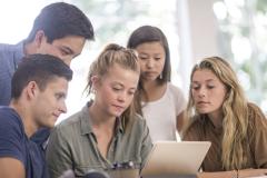 Un groupe de 5 étudiants étudie avec attention un contrat sur une tablette