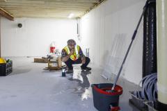 Un homme accroupi recherche les causes d'une inondation dans un sous-sol