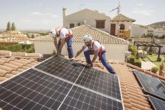 Deux ouvriers du bâtiment installent des panneaux solaires sur le toit d'une maison
