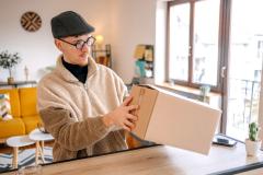 Un homme examine un colis sur le plan de travail de sa cuisine