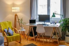 Chambre d'étudiant avec bureau, ordinateurs, fauteuil jaune et lampadaire allumé. 