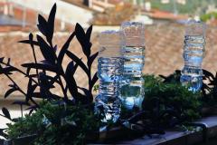 Des bouteilles d'eau en plastique percées et retournées permettent l'arrosage régulier des plantes d'une jardinière accrochée à la rambarde d'un balcon