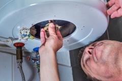 Un artisan réalise une intervention sur un ballon d'eau chaude
