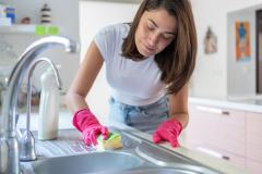 Une femme nettoie son évier en inox avec soin à l'aide d'une éponge