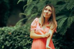 Une jeune femme qui se promène en extérieur se gratte le bras après une piqure de moustique
