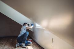 Homme peignant les murs d'un appartement.