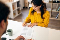 Une jeune femme d'origine asiatique aux cheveux longs signe un contrat lors d'un rendez-vous
