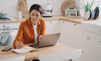 femme concentrée devant son ordinateur dans la cuisine