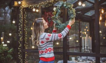 Une femme décorant l'extérieur de sa maison pour noël