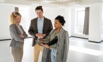 Un couple réalise un état des lieux avec une femme agent immobilier, qui tient un document dans ses mains pour signature