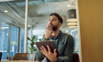 Un homme, réfléchissant, une tablette à la main