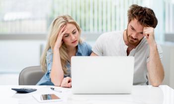 Un homme et une femme semblent dépités, assis côte à côte devant leur ordinateur