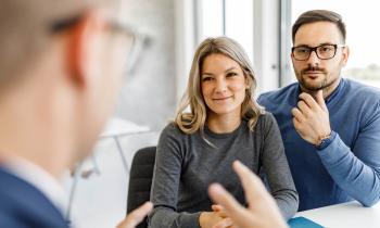 Un couple échange avec son banquier, assis devant un bureau