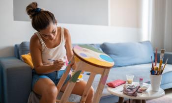 Jeune femme peint un tabouret en bois