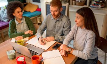 Trois personnes sont réunies autour d'une table de travail au domicile de l'une d'elles