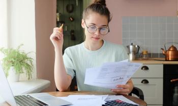 Une chose femme assise à un bureau fait des calculs, en étudiant divers documents au format papier