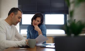 Un couple, assis autour d'une table, étudie avec attention un document au format papier