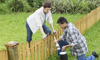 Un homme et une femme installent une petite clôture en bois commune en limite de leur terrain