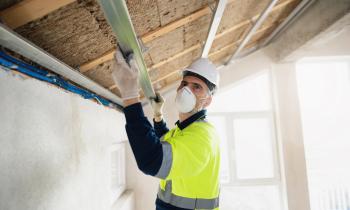 Un artisan procède à l'isolation de la toiture d'une maison