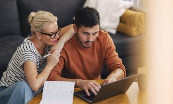 Un couple effectue des recherches sur un ordinateur portable, dans son salon