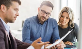 Un couple étudie des documents avec son banquier lors d'un rendez-vous