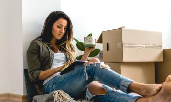 Femme répondant au quiz déménagement sur sa tablette au milieu de ses cartons