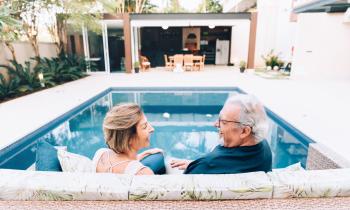 couple de retraités devant la piscine de leur résidence secondaire