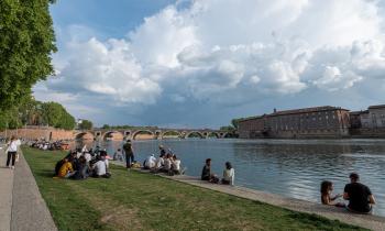 Des étudiants sont assis sur l'herbe sur les berges de la Garonne, à Toulouse, par une journée ensoleillée