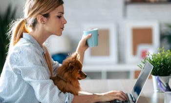 femme tient une tasse et recherche à faire un investissement immobilier  devant son ordinateur