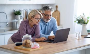 Couple fait des recherches sur les  dispositifs de défiscalisation depuis son ordinateur dans sa cuisine 