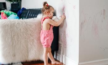 Une petite fille dessine avec un marqueur sur les murs blancs du salon