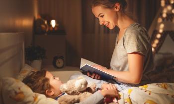 Une maman, assise sur le lit de son petit garçon, lui lit une histoire avant qu'il s'endorme
