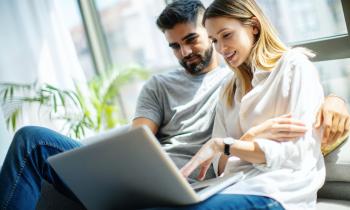 couple-regarde-son-ordinateur-adossé-à-la-baie-vitrée