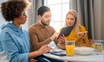 Colocataires lisant sur une tablette pendant le petit déjeuner. 