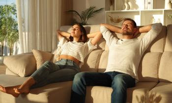 Jeune couple profite du soleil à l'aise dans le canapé du salon