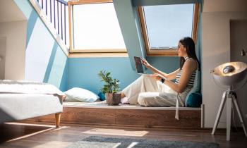 femme regarde son ordinateur portable installée sous son velux securisé