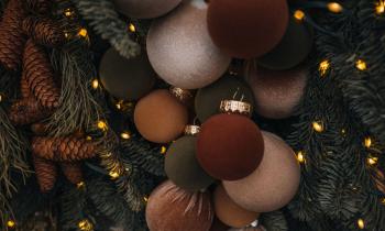 Boules de Noël allant du brun au safran accrochées sur un sapin