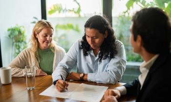 Un couple signe une offre d'achat sur les conseils d'un agent immobilier