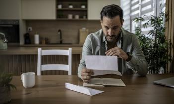 Un homme lit, préoccupé, le contenu d'un courrier qu'il vient de recevoir