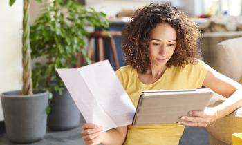Une femme aux cheveux bouclés consulte ses comptes sur une tablette