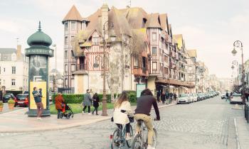Un jeune couple arpente l'une des artères principales de Deauville à vélo