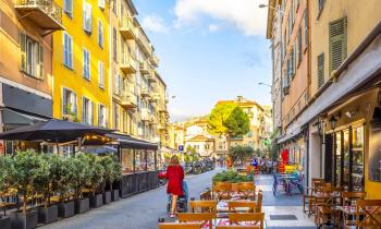 Une femme avec une poussette se promène dans une rue du Vieux Nice