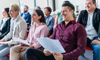 Un groupe de personnes assises côte à côte, tenant la convocation dans les mains, participe à une réunion de copropriété