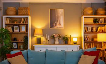 Petit salon cosy éclairé, avec un canapé bleu et des coussins rouges. 